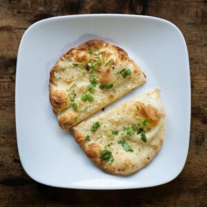 Appetizing garlic naan bread on a white plate