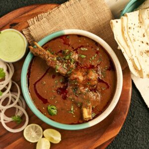 A sumptuous Indian curry served with flatbread and garnished with onions and herbs.