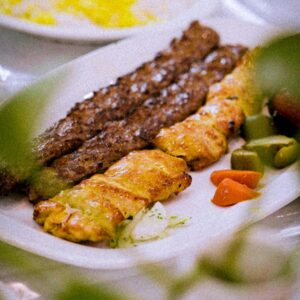 A mouth-watering plate of mixed grilled kebabs with colorful sides and saffron rice.