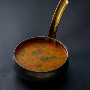 A close-up shot of Indian dal garnished with herbs in a copper pot
