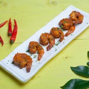 Delicious spicy grilled shrimp garnished with herbs and served with red chili peppers.