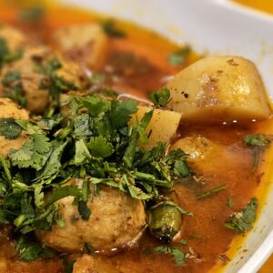 Close-up of a flavorful Indian aloo kofta curry garnished with fresh coriander.