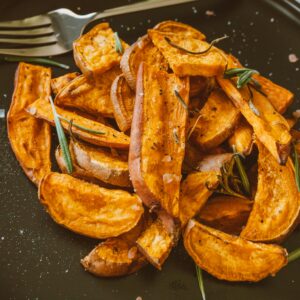 Close-up of crispy sweet potato wedges topped with rosemary
