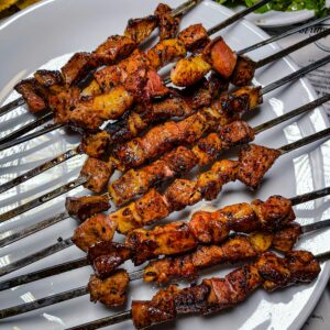 A close-up of flavorful grilled meat skewers on a white plate