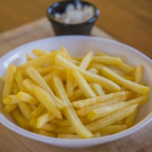 Crispy golden french fries served in a white ceramic bowl on a wooden table.