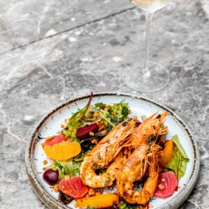 Delicious seafood salad featuring grilled prawns and fresh vegetables on a ceramic plate.