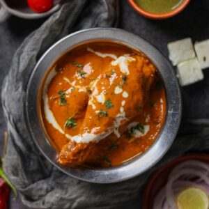 Mouth-watering butter chicken curry garnished with cream and herbs