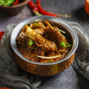 Close-up of a spicy mutton curry served in a traditional copper bowl